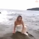 파도가 치는 바위에서 사진 찍는 여자 이미지